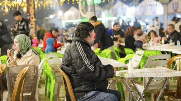 Muslim families and individuals gather at outdoor tables for a mass community Iftar meal under festive Ramadan lights in Gaziantep, Turkey on March 11, 2026, Gaziantep, Turkey
