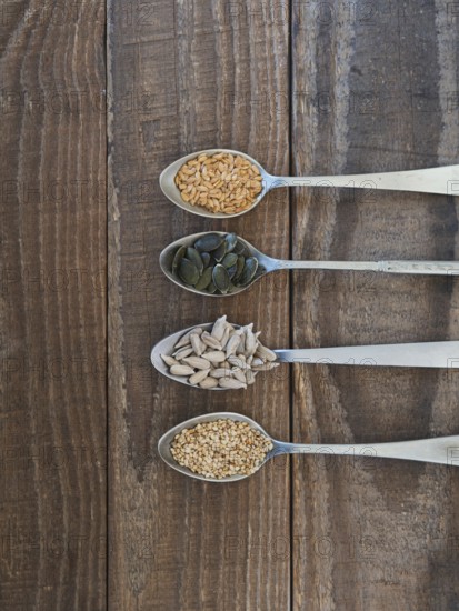 Various healthy seeds filling spoons on a rustic wooden background