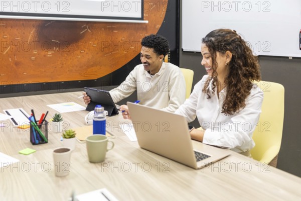 A team engaged in a productive meeting in a modern office. Colleagues are using laptops and tablets at a conference table, fostering collaboration and creativity in the workplace