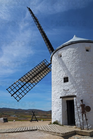 White windmill with a metal device of Don Quixote in front, under a clear sky, rural environment, Consuegra, Toledo, Castilla-La Mancha, Route of Don Quixote, Spain