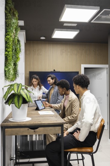 An inspiring office setting where professionals engage in a collaborative meeting. Modern decor, including wooden accents and greenery, complements digital technology