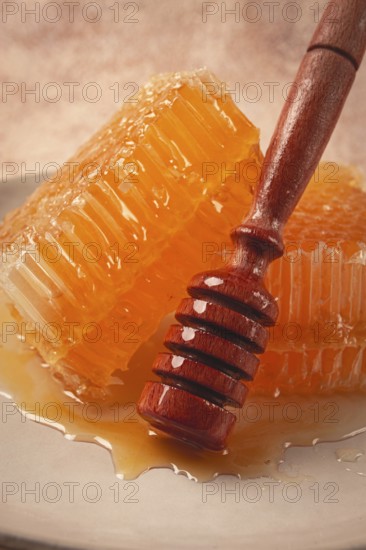 Honeycomb, with a wooden spoon-spindle, on a plate, no people