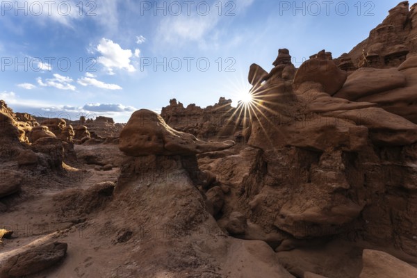 Goblin Valley State Park in Utah features unique rock formations glowing under the sun's rays. The intricate sandstone landscape creates a captivating and surreal natural scene