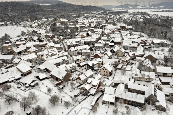 Village in winter with snow-covered half-timbered houses and trees under grey skies, Herleshausen in northern Hesse
