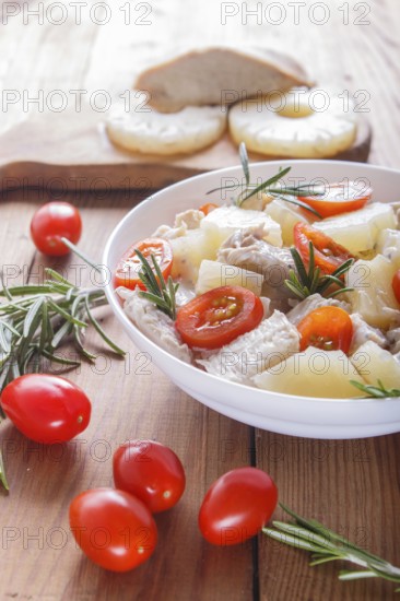 Chicken fillet salad with rosemary, pineapple and cherry tomatoes on brown wooden background. close up