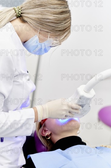 A dental professional in a clinic performing a specialized oral care procedure using modern equipment. The setting emphasizes hygiene and advanced dental technology