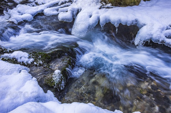 Small watercourse in winter with ice floes and mossy stones, Brühlbach below Urach Waterfall, Bad Urach, Swabian Alb, Baden-Württemberg, Germany