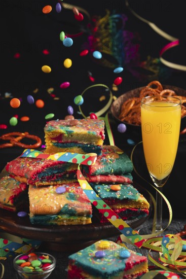 Colourful pieces of cake with sparkling wine and flying chocolate drops in a lively party atmosphere, carnival