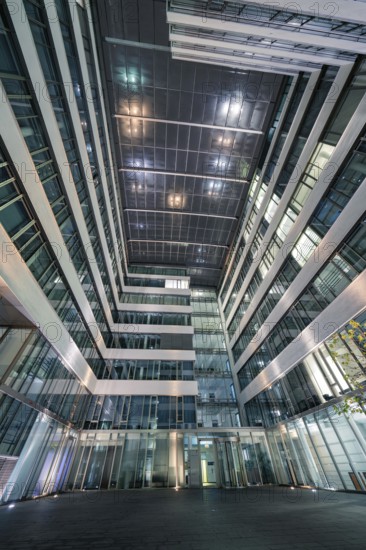 Modern building complex with illuminated inner courtyard and glass structure, Stuttgart, Germany