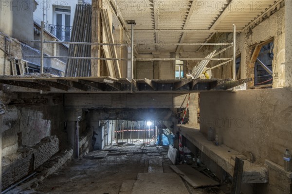 A construction site inside a partially renovated building features an exposed concrete structure, temporary railings, and construction materials