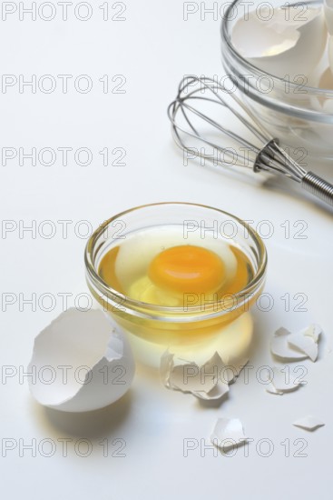 Egg whites and egg yolks in glass bowl and egg shells, whisk