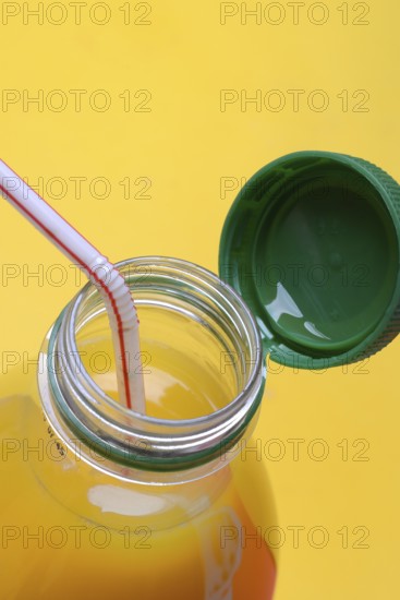 Orange juice in plastic bottle with cap and straw