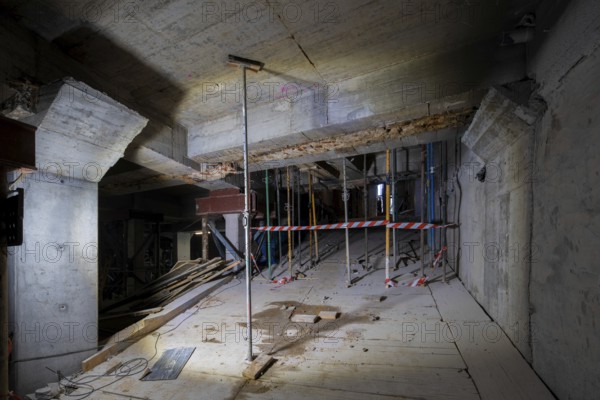 A detailed view of a construction site showing a partially completed structure. Wooden planks, metal supports, and caution tape are visible, emphasizing a work in progress theme