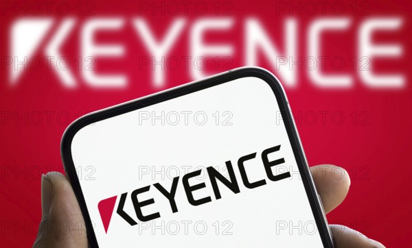 Keyence logo is displayed on smartphone. Keyence is a Japanese company that manufactures automation equipment and precision instruments.