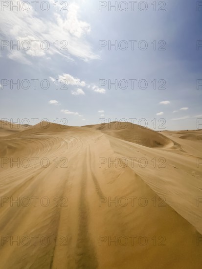 Sweeping views of Ica's vast sand dunes stretch under a vibrant blue sky, showcasing the unique desert landscapes of Peru