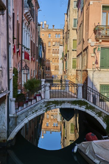 View from a gondola on a waterway in Venice going through the houses on a quiet and sunny morning in winter, Italy