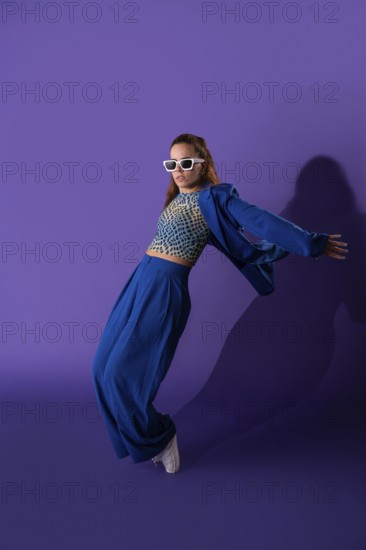 A young woman exudes grace and energy as she performs a dynamic dance against a striking purple background. Her stylish attire and poised movement captivate the viewer
