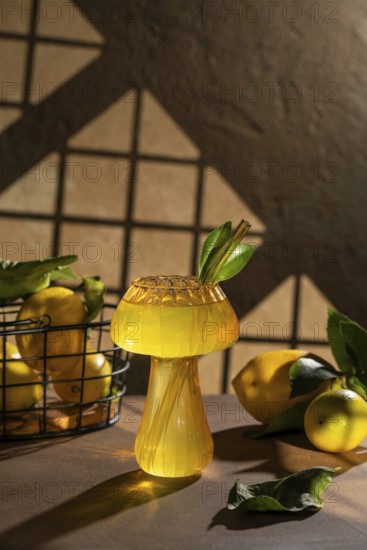 A refreshing lemon drink served in an artistic glass, adorned with green leaves and surrounded by fresh lemons. Perfect for summer refreshment and visual delight