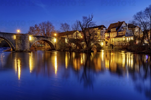 Illuminated bridge reflected in the blue water at night, peaceful atmosphere, The historic Bartenwetz stone bridge in Melsungen