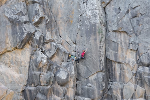 Climbers scale a rugged cliff using traditional techniques, highlighting skill, adventure, and a deep connection with nature. The rock formation offers a stunning backdrop
