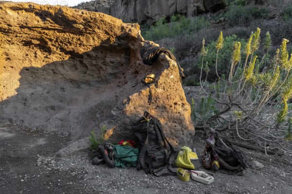 Climbing gear and supplies laid out on the ground near a rugged boulder, surrounded by natural scenery, capturing the essence of outdoor bouldering adventure