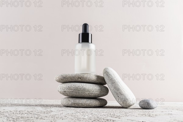 A minimalist skincare concept with a frosted glass dropper bottle placed elegantly on a stack of smooth stones The neutral background enhances the serene composition