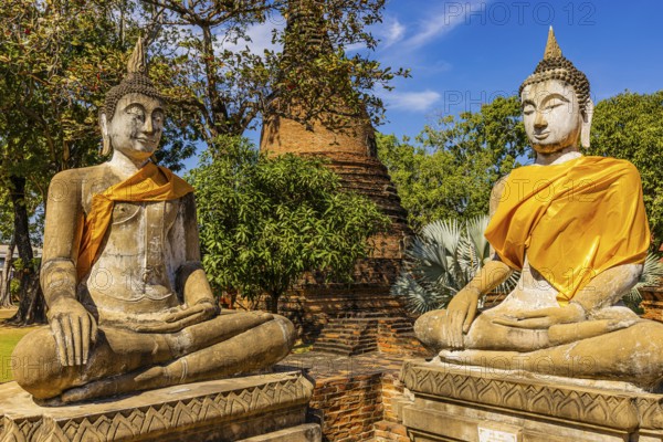 Stone Buddha statues decorated with yellow cloths, historic Buddhist temple complex, Ayutthaya, Thailand