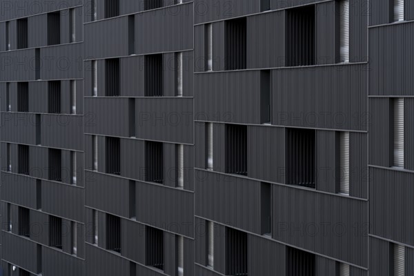 Modern building featuring a distinct, sustainable architectural style with vertically aligned, repeated portal-like window openings. The design emphasizes low-emission construction materials and efficient energy use