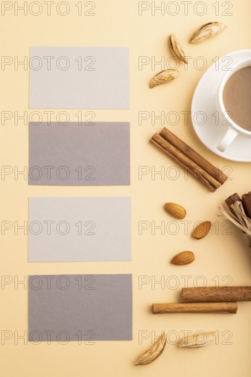 Composition of gray paper business cards, almonds, cinnamon and cup of coffee. mockup on orange background. Blank, top view, still life, flat lay, copy space