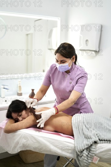 A skilled therapist provides a soothing massage to a client in a contemporary beauty salon. The tranquil setting features soft lighting and calming decor, ensuring relaxation and comfort