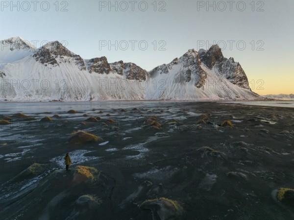 A stunning winter view of Stokksnes Beach in Iceland, featuring rugged snow-capped peaks against a tranquil twilight sky. Perfect for nature and travel themes