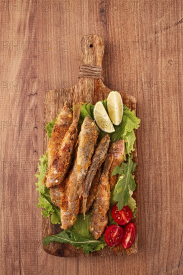 Fried crispy red mullet fish, on a wooden chopping board, with lime, no people
