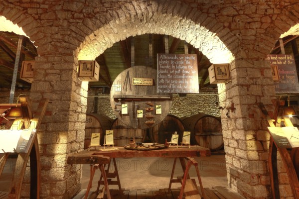 Atmospheric shot of a rustic wine cellar with wooden table and tools under brick arches, Achaia Clauss Winery, Patras, Peloponnese, Greece