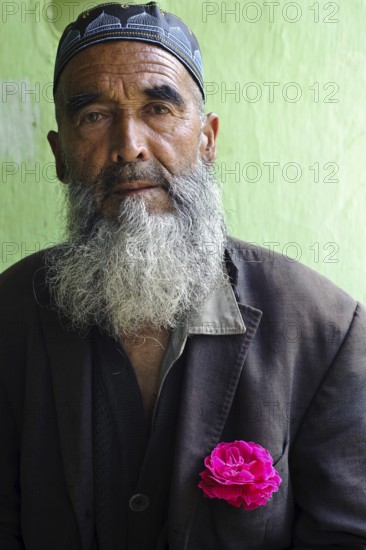 Portrait of a muslim man from the Uzbek ethnic group, Kyrgyzstan. Wearing a pink rose in the pocket