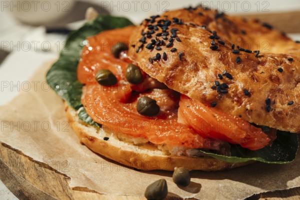 Close-up of a tasty bagel topped with smoked salmon, capers, and fresh greens. Perfect for breakfast or brunch, the bagel features a golden, sesame seed-crusted exterior