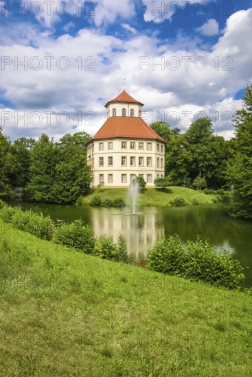 Oppenweiler moated castle, built in the 18th century, classicist style, castle complex in unequal-sided octagon, today town hall, architecture, tent roof with pavilion top, windows, lake, castle lake, water features, island, park, garden designer Friedrich Ludwig von Sckell, meadow, lawn, trees, bushes, shrubs, cloudy sky, Oppenweiler, Rems-Murr district, Baden-Württemberg, Germany
