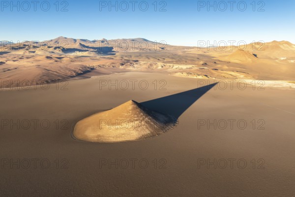 From above, the Cono de Arita in Salta, Argentina forms a striking natural landmark amidst the vast, arid landscape. The distinct sharp peak rises dramatically from the flat salt flats of the Puna region