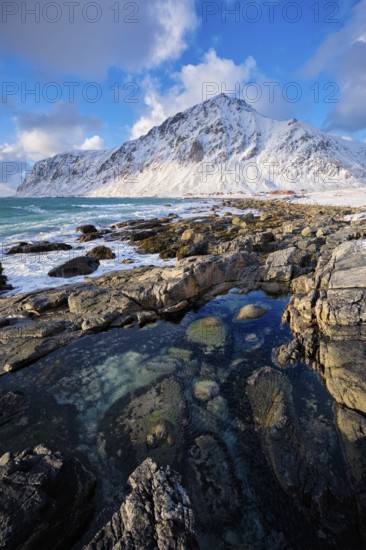 Beach of Norwegian sea on rocky coast in fjord on sunset in winter. Vareid beach, Lofoten islands, Norway