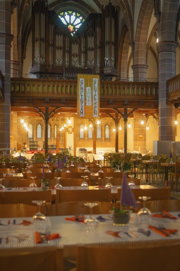 Interior view of a church with organ in the background and laid tables in the foreground, Vesperkirche Calw, Black Forest, Germany