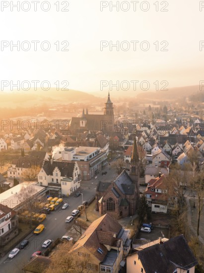 A church and a village in the evening light with a view of hills and trees, Weil der Stadt, Böblingen district, Germany