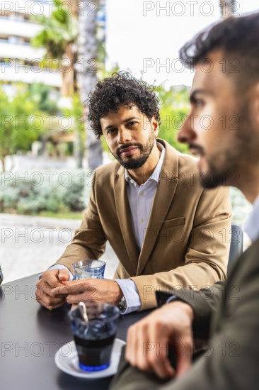 Vertical photo of a businessman listening to colleagues sitting in a cafeteria