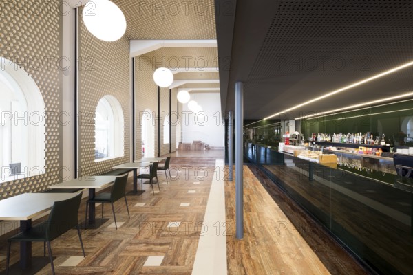 This spacious bar features modern architecture with sleek furniture, elegant lighting, and a polished bar area, creating a stylish and inviting atmosphere