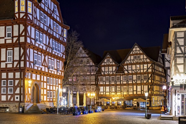 Night scene with illuminated half-timbered houses and a café in a rustic setting, The old town centre of Melsungen