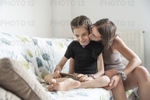 A family shares a tender moment with a disabled girl who has a tracheostomy using phone. The image shows love, support, and togetherness, highlighting the importance of family bonds in overcoming challenges