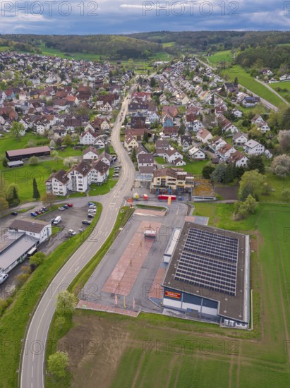 Roads cross a village with a building and neighbouring fields from an aerial perspective, Ostelsheim, district of Calw, Germany