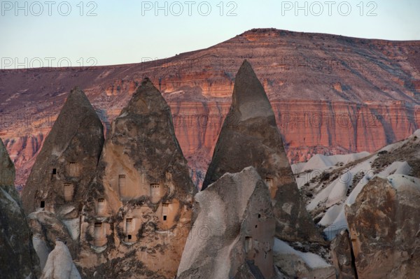 Rock carved dwellings in the dramatic cone shaped rocks of the Rose Red Valley, amazing Anatolian landscape, Cappadocia, Turkey