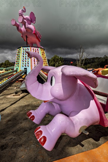 Pink elephant figures of a stopped carousel on a cloudy day, amusement park and carousel in Nuwara Eliya Sri Lanka