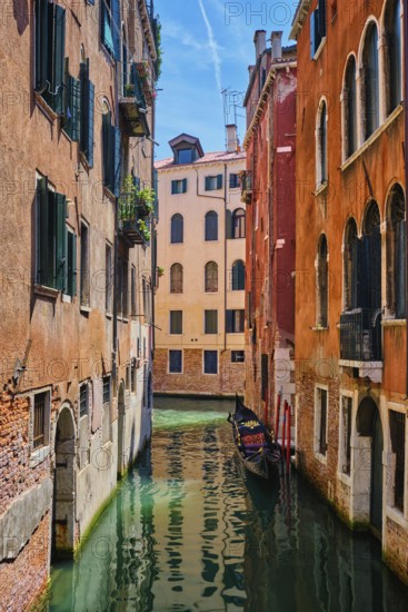 Narrow canal between colorful old houses with gondola boat in Venice, Italy