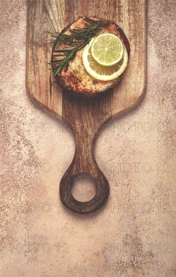 Salmon steak, fried, on a cutting board, top view, rosemary, lemon and lime, homemade, one serving, no people