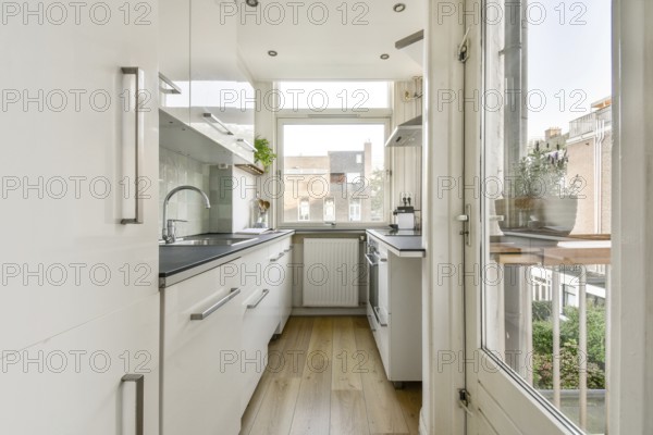 A contemporary kitchen featuring sleek cabinetry, natural light flooding in from large windows, and wooden flooring. A perfect blend of style and functionality
